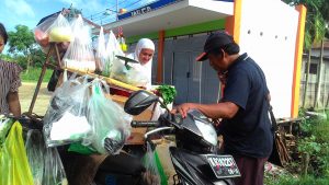 Bang Kus (46), sedang melayani pelanggannya membeli sayur keliling.(foto:dik)